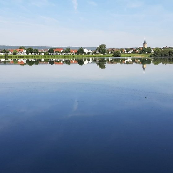 Das Foto zeigt Ebing im Sommer vom Baggersee her
