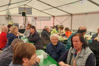 Gäste sitzen im Bierzelt an Tischen zum Kaffeeplausch