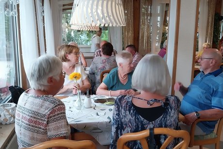 Mitglieder sitzen im Gasthaus an Tischen und unterhalten sich.