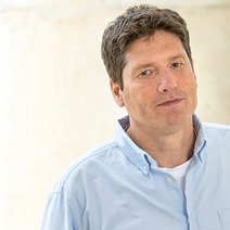 Auf dem Bild ist ein Mann mit kurzen braunen Haaren und einem hellblauen Hemd zu sehen