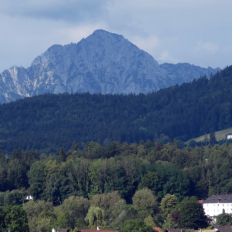 Kirche in Ainring mit Staufen im Hintergrund und eingefügtem Wappen von Ainring