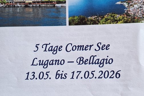 Ein gr&uuml;ner Bus durchquert die Wiesenlandschaft mit Bergen im Hintergrund.