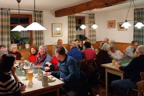 Mitglieder und G&auml;ste sitzen in der Gaststube beim Heringessen und unterhalten sich.