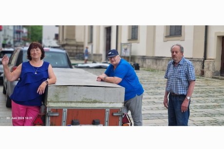 Mitglieder vom VdK stehen vor dem Materialanhänger des VdK nach dem Abbau des Infostands des VdK auf dem Stadtplatz in Traunstein