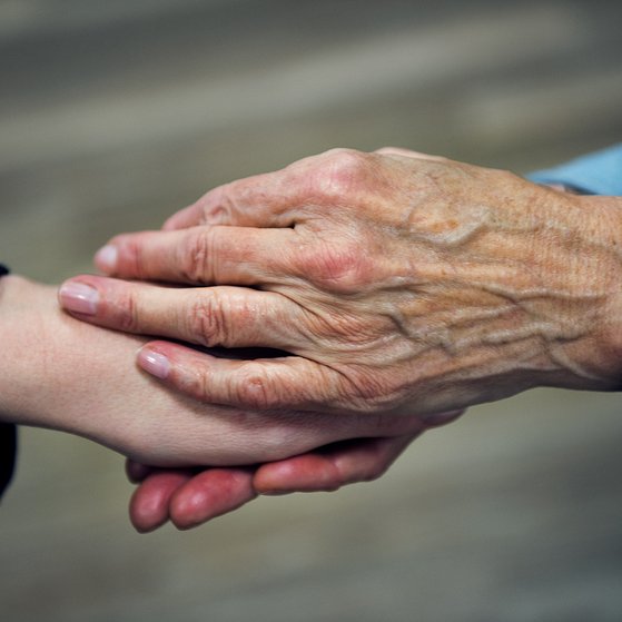 Die Hand einer &auml;lteren Frau h&auml;lt die Hand einer j&uuml;ngeren Frau in einer tr&ouml;stenden Geste.