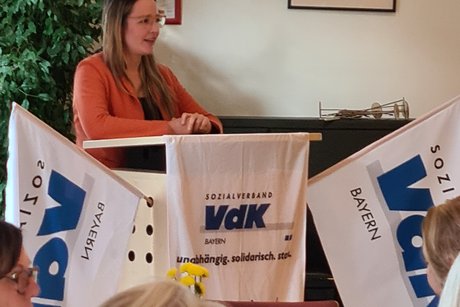 Bettina Stuber Frau Stuber hinter dem Pult, geschmückt mit 2 VdK-Fahnen rechts und links und mittig das VdK OV Pfaffenhofen Vereinstuch