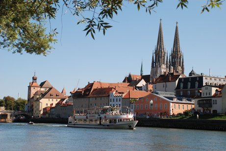 Vor der Stadtsilhouette von Regensburg fährt ein Schiff auf der Donau.