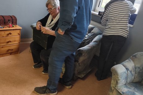 Auf dem Foto fummelt Frau Römmelt an einem Koffer herum und probiert die gefundene Zahlenkombination aus.