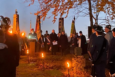 Auf dem Bild sieht man die Redner zum Volkstrauertag und die Vereinsfahnen mit Ihren Trägern im Fackelschein