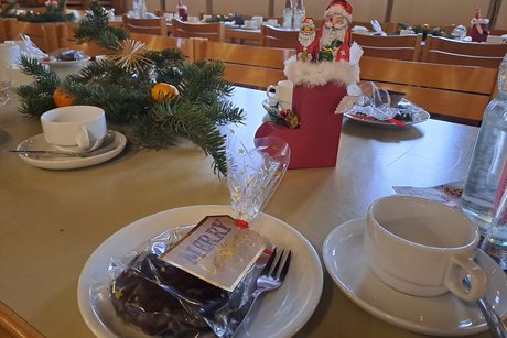 Auf dem Bild sieht man einen Tisch mit Kaffeetassen, einen Nikolausstiefel, Tannenzweige mit Mandarinen dekoriert.