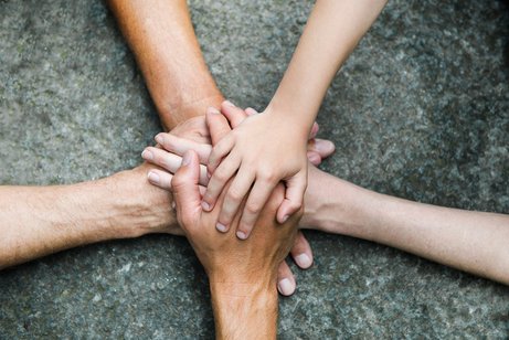 Hände zusammen für Gemeinschaft Fünf Personen legen jeweils eine Hand aufeinander, so dass ein Kreis bzw. ein Stern entsteht