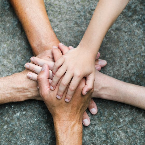 Hände zusammen für Gemeinschaft Fünf Personen legen jeweils eine Hand aufeinander, so dass ein Kreis bzw. ein Stern entsteht