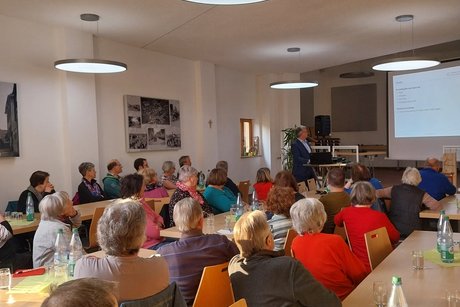 Mitglieder sitzen im Vortragsraum und hören einem Referenten zu.