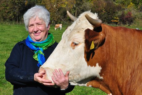 links stehend Frau Luttner-links stehend eine Kuh, welche Frau Luttner an der Schnauze streichelt