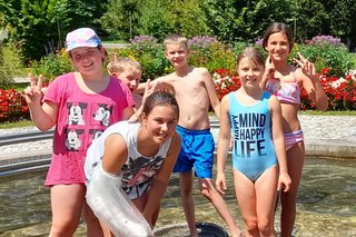 Gruppe von Kindern stehen im Wasser beim Brunnen