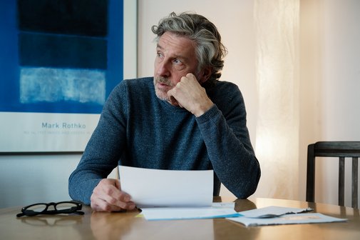 Besorgter älterer Mann Ein älterer Mann sitzt an einem Tisch, vor sich einen Brief. Er schaut besorgt in die Ferne, stützt das Kinn in die Hand.