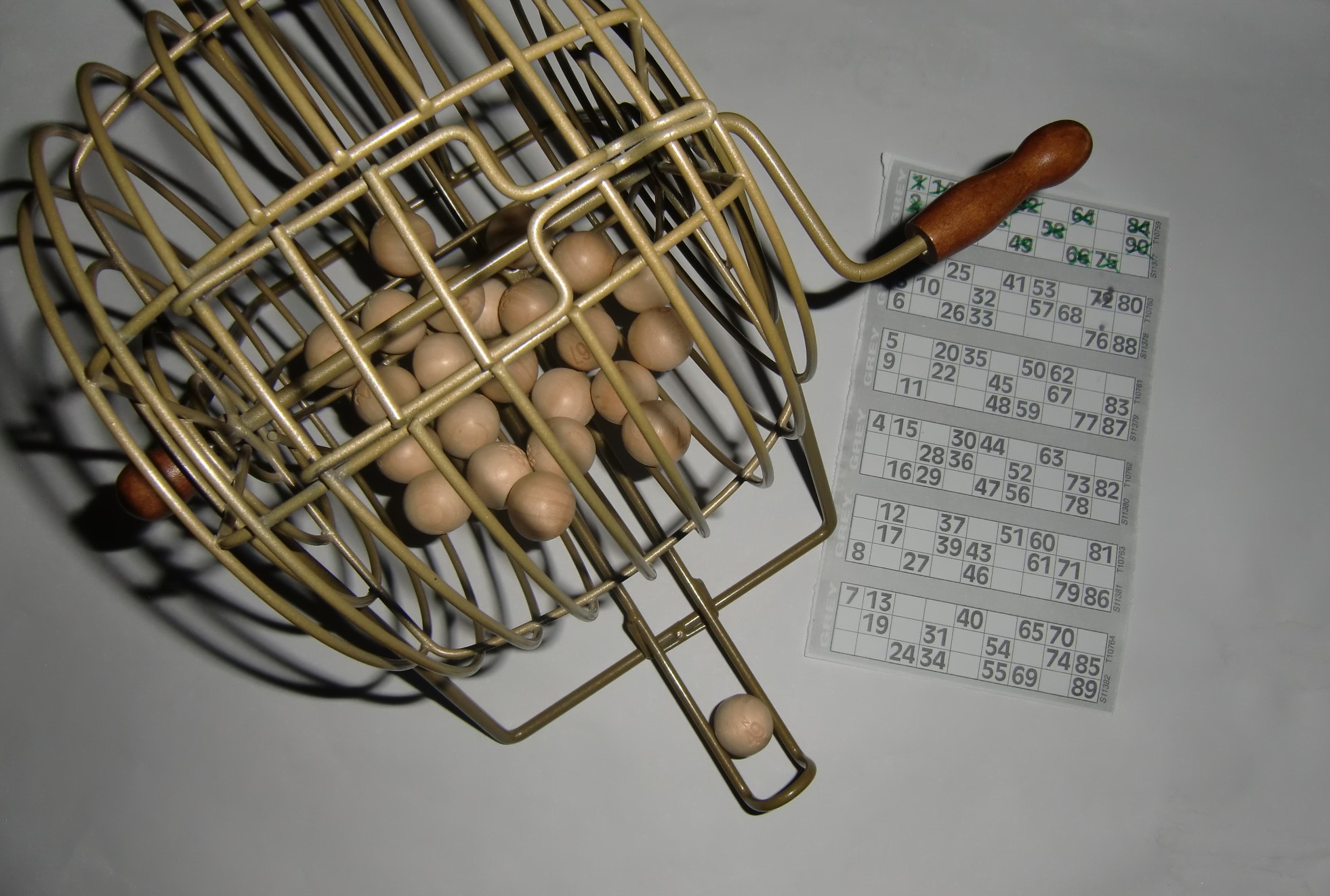 Bild zeigt eine Bingo-Trommel mit Kugeln auf diesen Zahlen sind, und ein Bingo-Spieleblatt mit verschiedenen Zahlen.