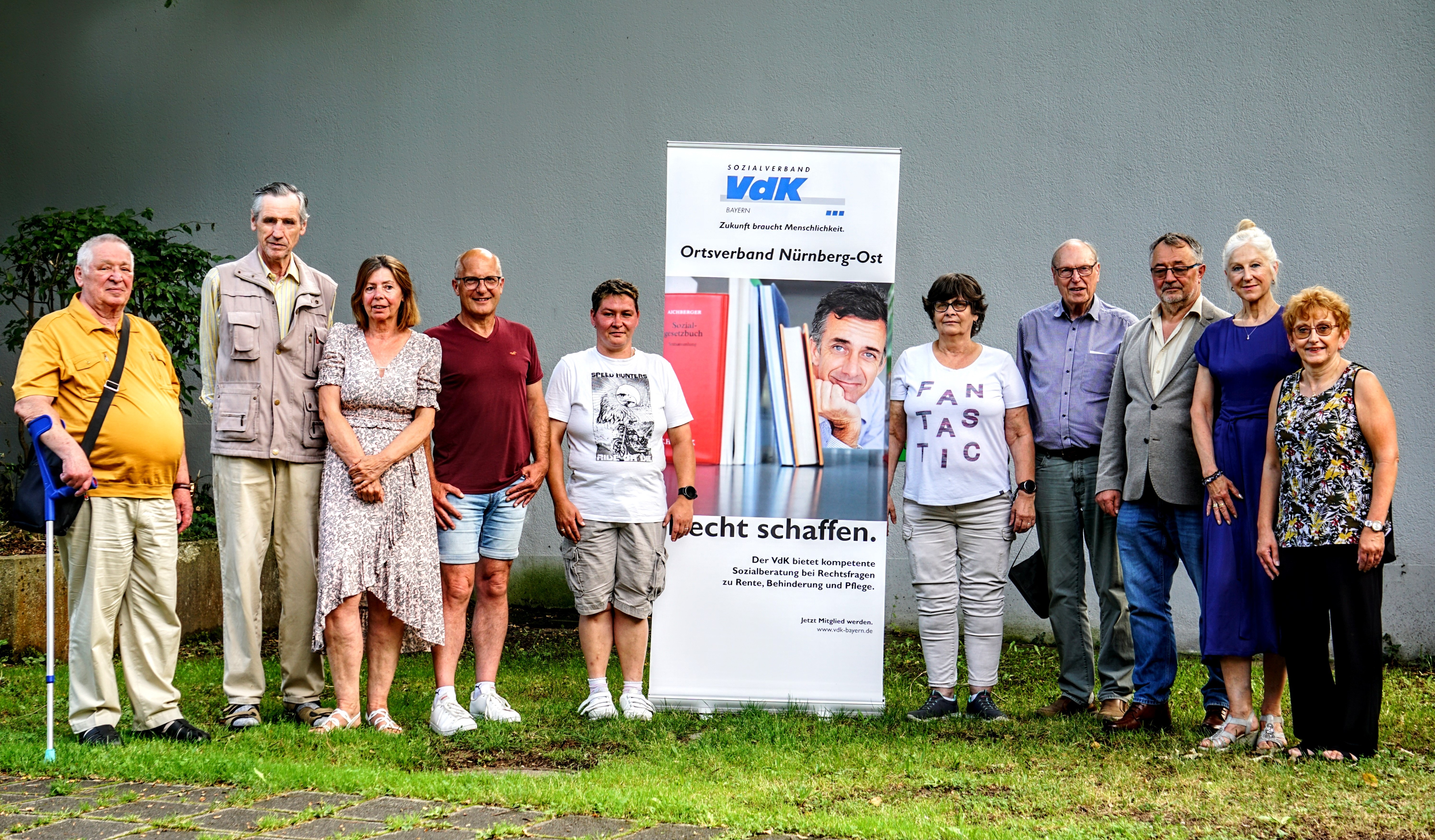 10 stehende Personen vor einem VdK-Aufsteller