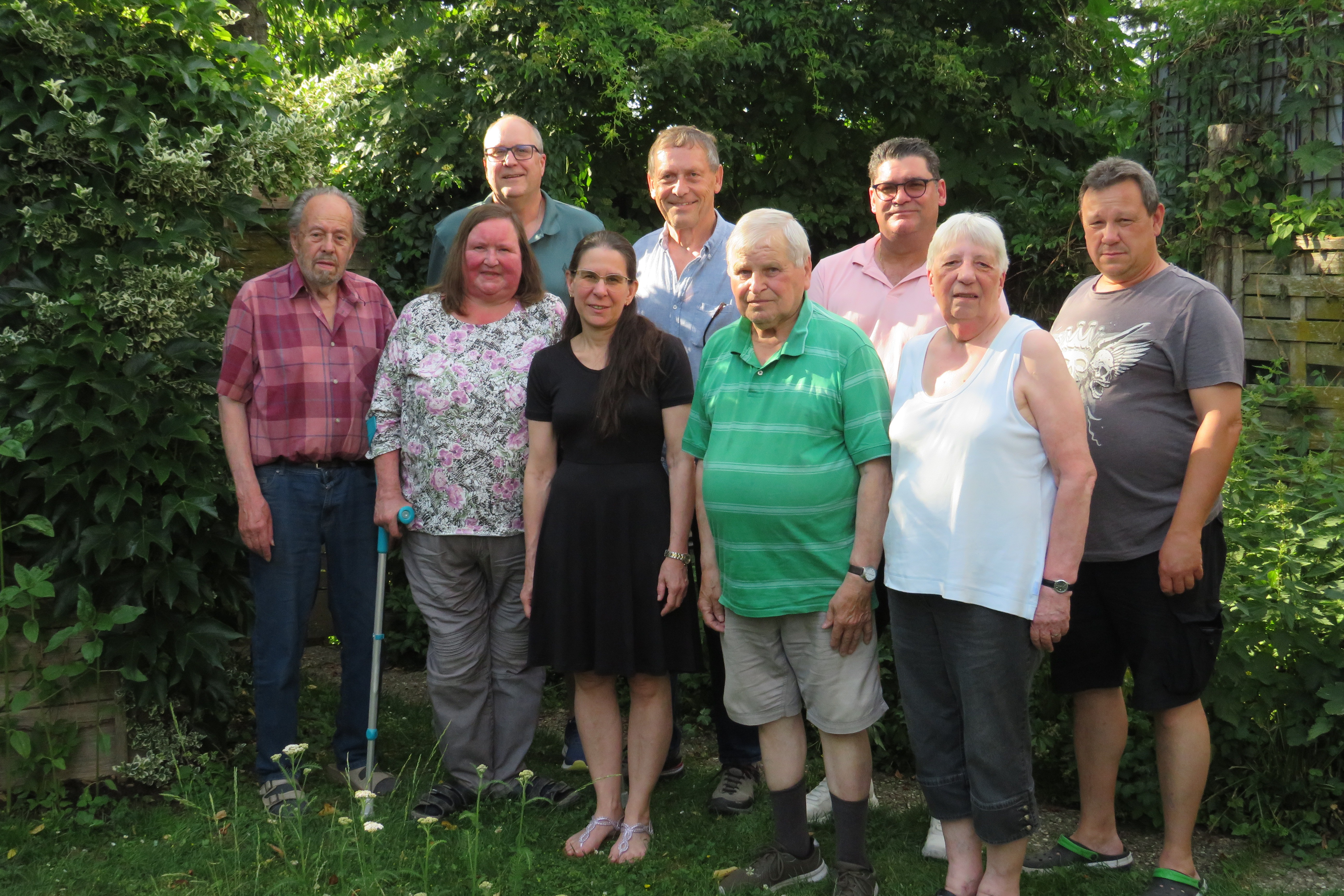 Das Bild zeigt die neun Vorstandsmitglieder des VDK Ortsverbandes Trostberg auf einem Gruppenfoto, das nach einer Vorstandssitzung im Garten des Ehrenvorsitzenden gemacht wurde.