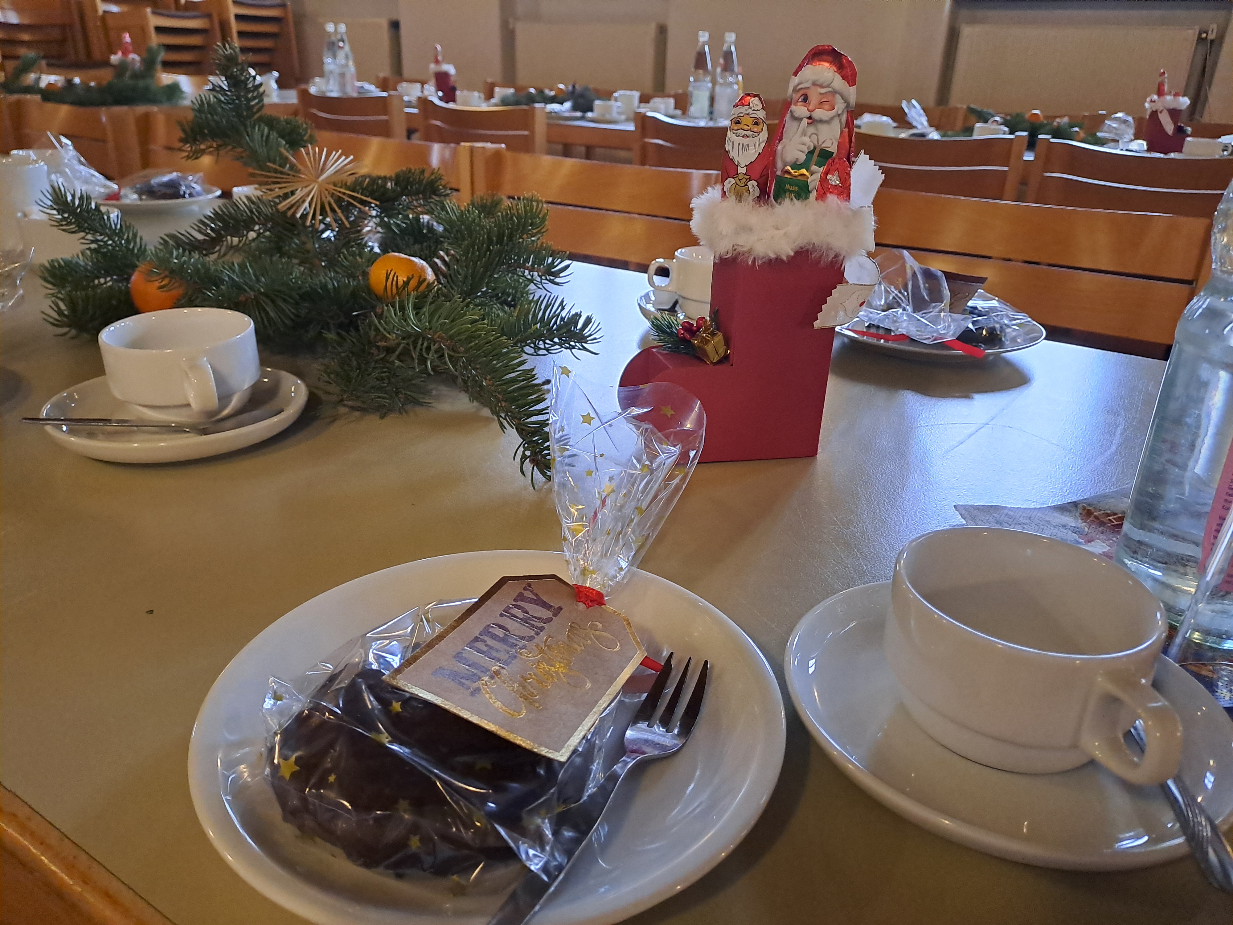 Auf dem Bild sieht man einen Tisch mit Kaffeetassen, einen Nikolausstiefel, Tannenzweige mit Mandarinen dekoriert.