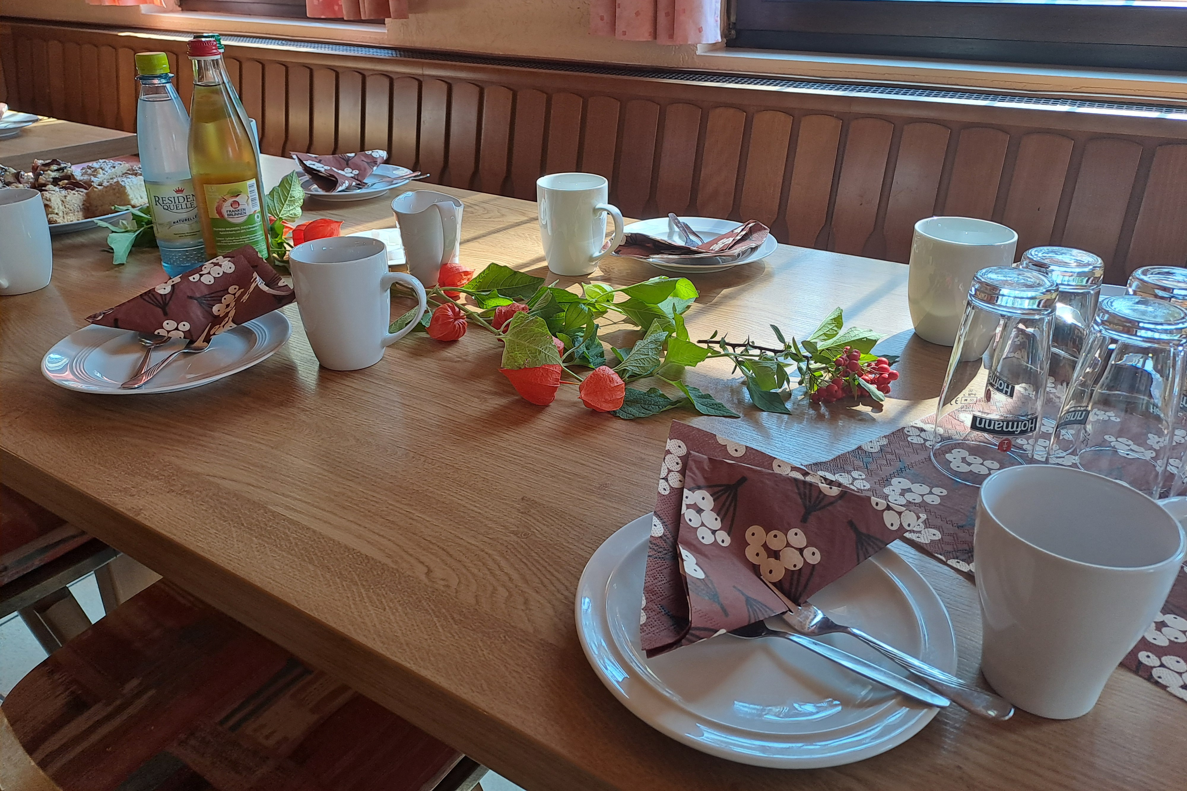 Auf dem Bild sieht man einen Tisch mit Kaffeetassen, Getr&auml;nken und Blumendekoration