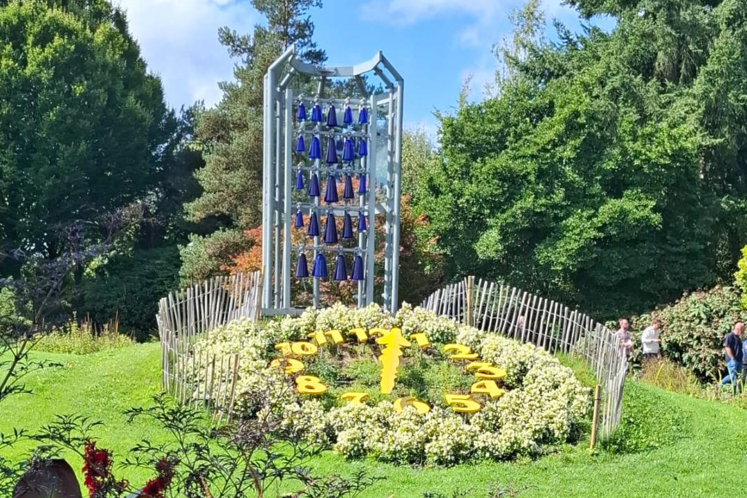 Zifferblatt an einem gr&uuml;nen Hang, HIndergrund Glasspiel aus blauen Flaschen