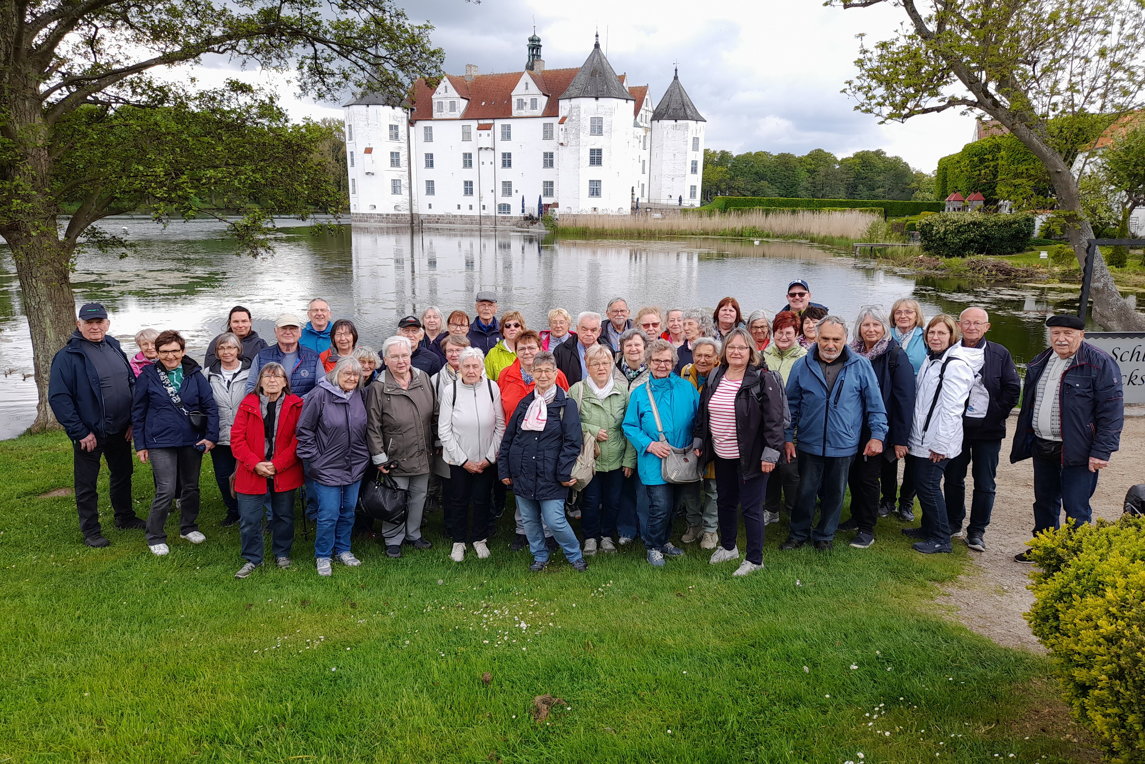 Die Reisegruppe des VdK vor einem See mit einem Schloss im Hintergrund