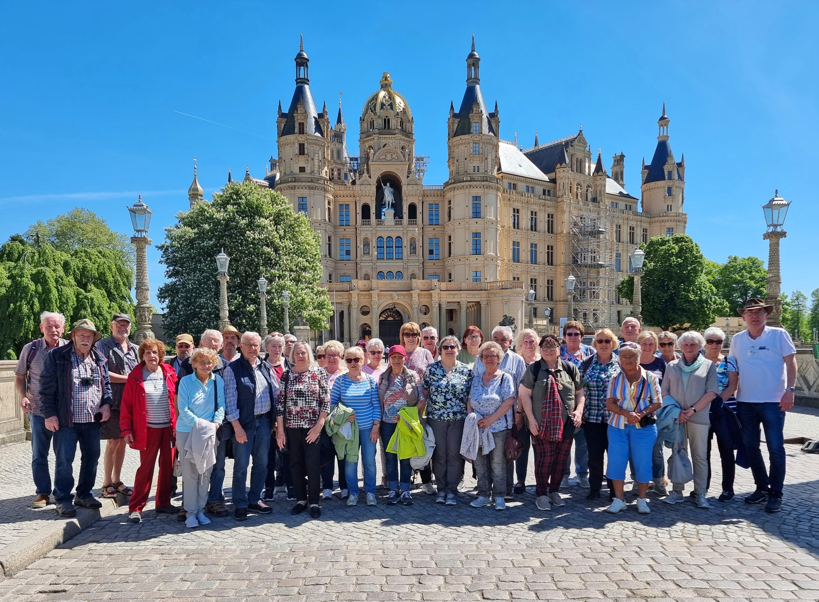 Abgebildet ist die Reisegruppe des VdK-Kreisverbandes Hof vor dem von einer goldenen Kuppel und zahlreichen Türmen gekrönten Schweriner Schloss