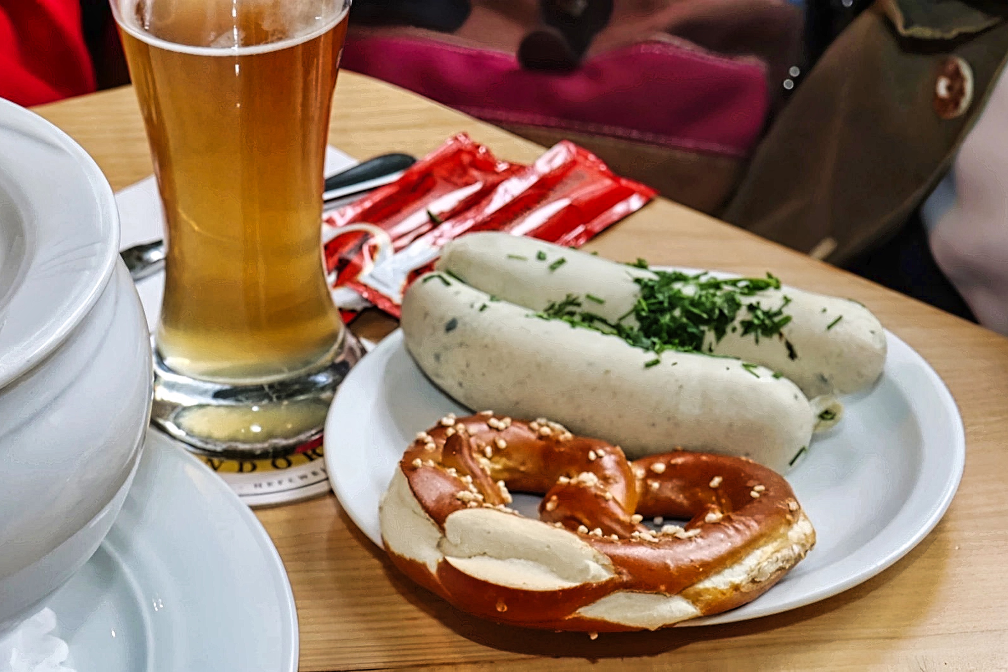 Weißwurstfrühstück Auf dem Tisch steht Teller mit leckeren Weißwürsten mit einer Breze und einem Weißbier