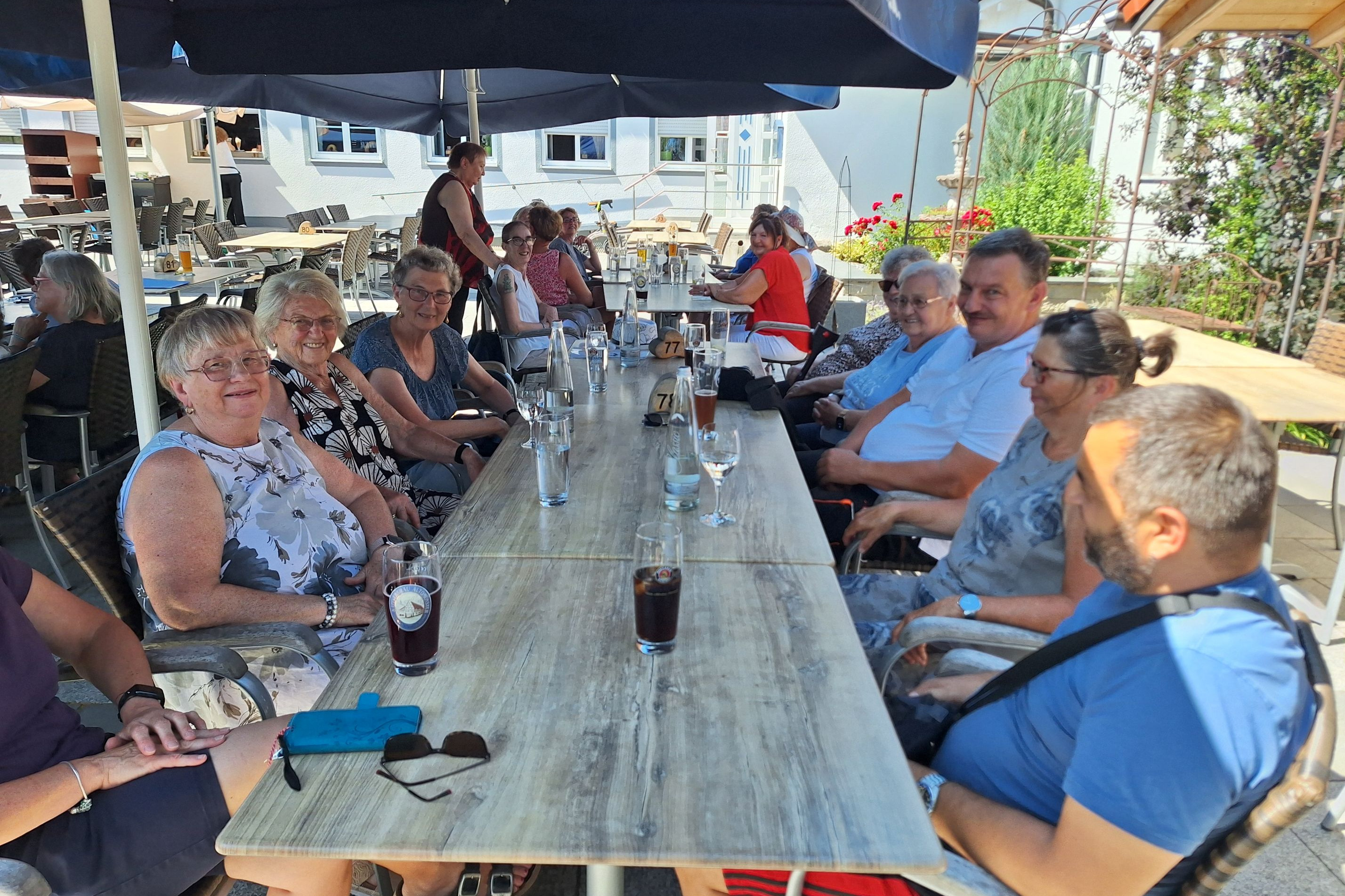 Biergartenbesucher im Schatten der Sonnenschirme