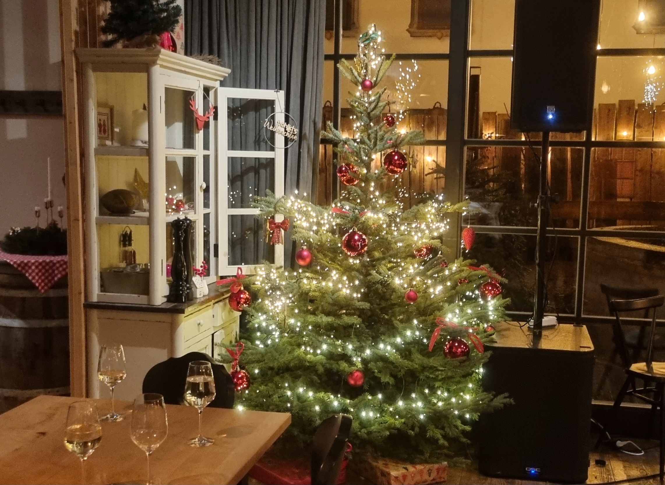 Auf dem Bild sieht man einen hübsch geschmückten Christbaum in einem schönen abgedunkelten Raum