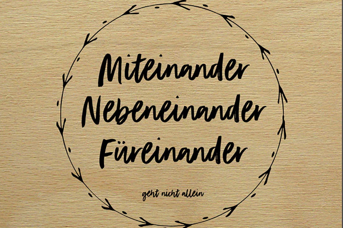 Zusammen stark! Zu sehen eine Holztafel mit der Aufschrift, Miteinander, Nebeneinander, Füreinander.