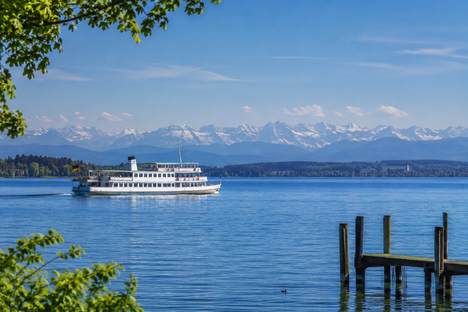 Ein wei&szlig;er Ausflugsdampfer auf einem blauen See mit Bergen im Hintergrund