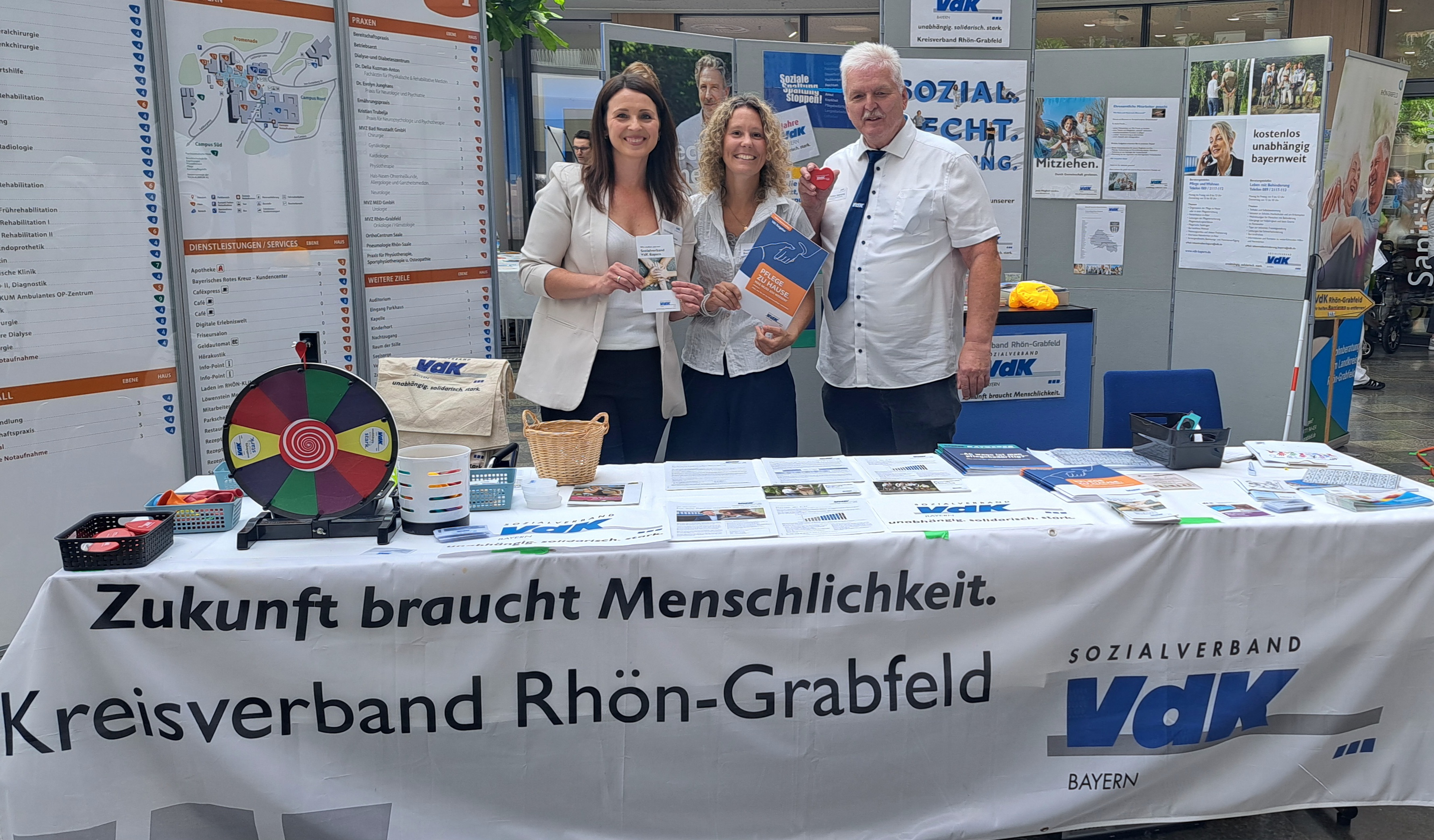 3 Personen an einem Infostand