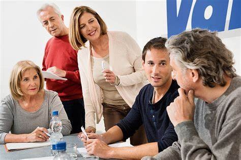 5 Menschen in einer Diskussion am Besprechungstisch.