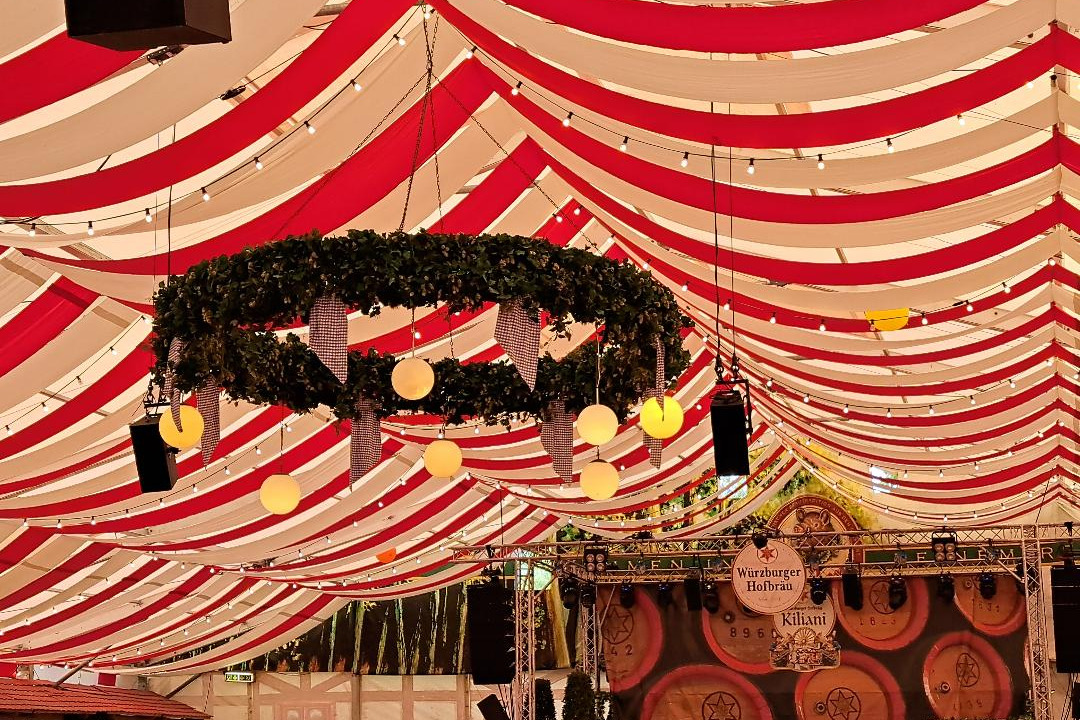 Decke des Festzeltes mit Kranz und Lichtern, im Hintergrund Bierf&auml;sser