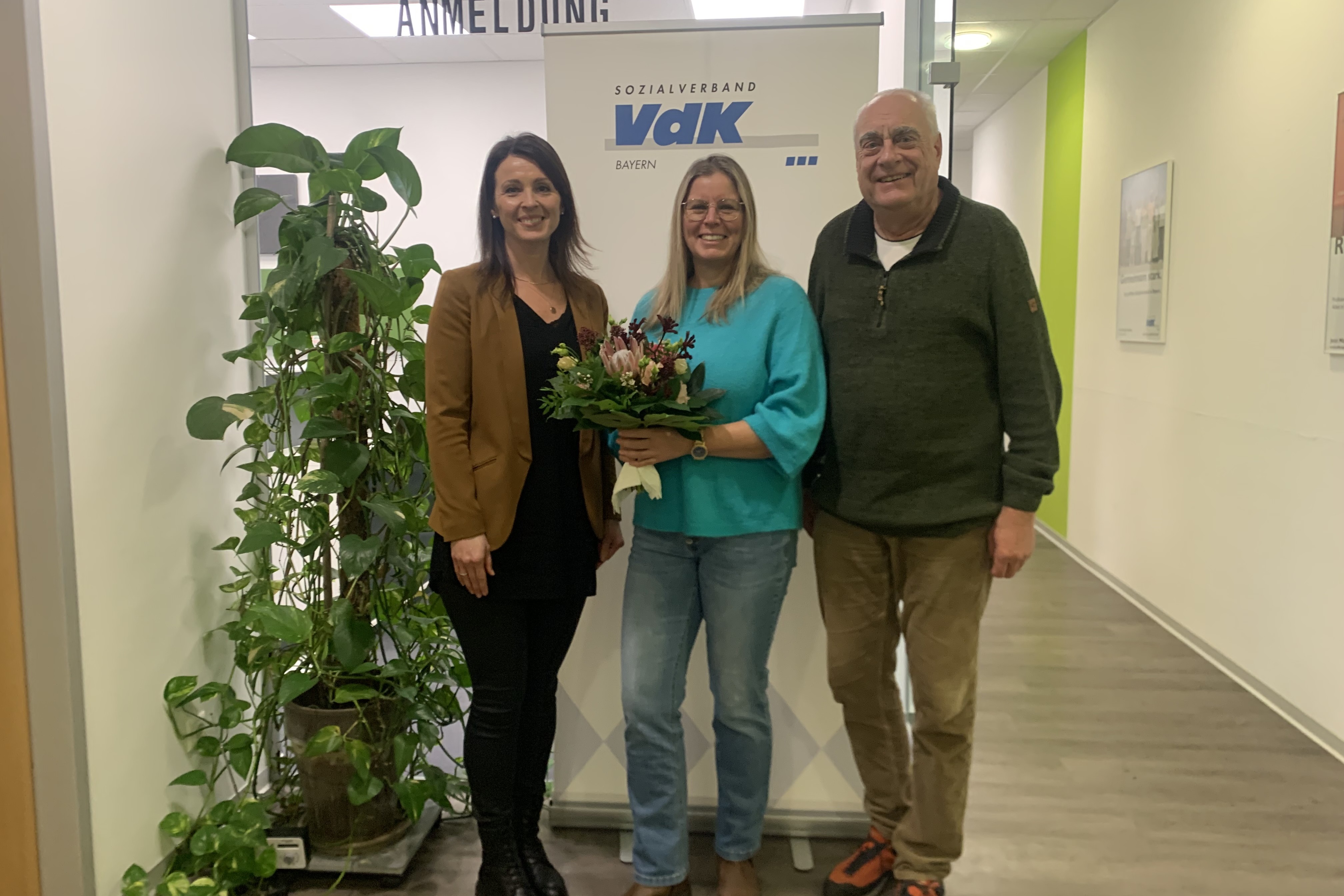 von links: Anna Ortmann, Anika Haid, Dirk Brosge 3 Personen. In der Mitte die geehrte Frau mit Blumenstrauß