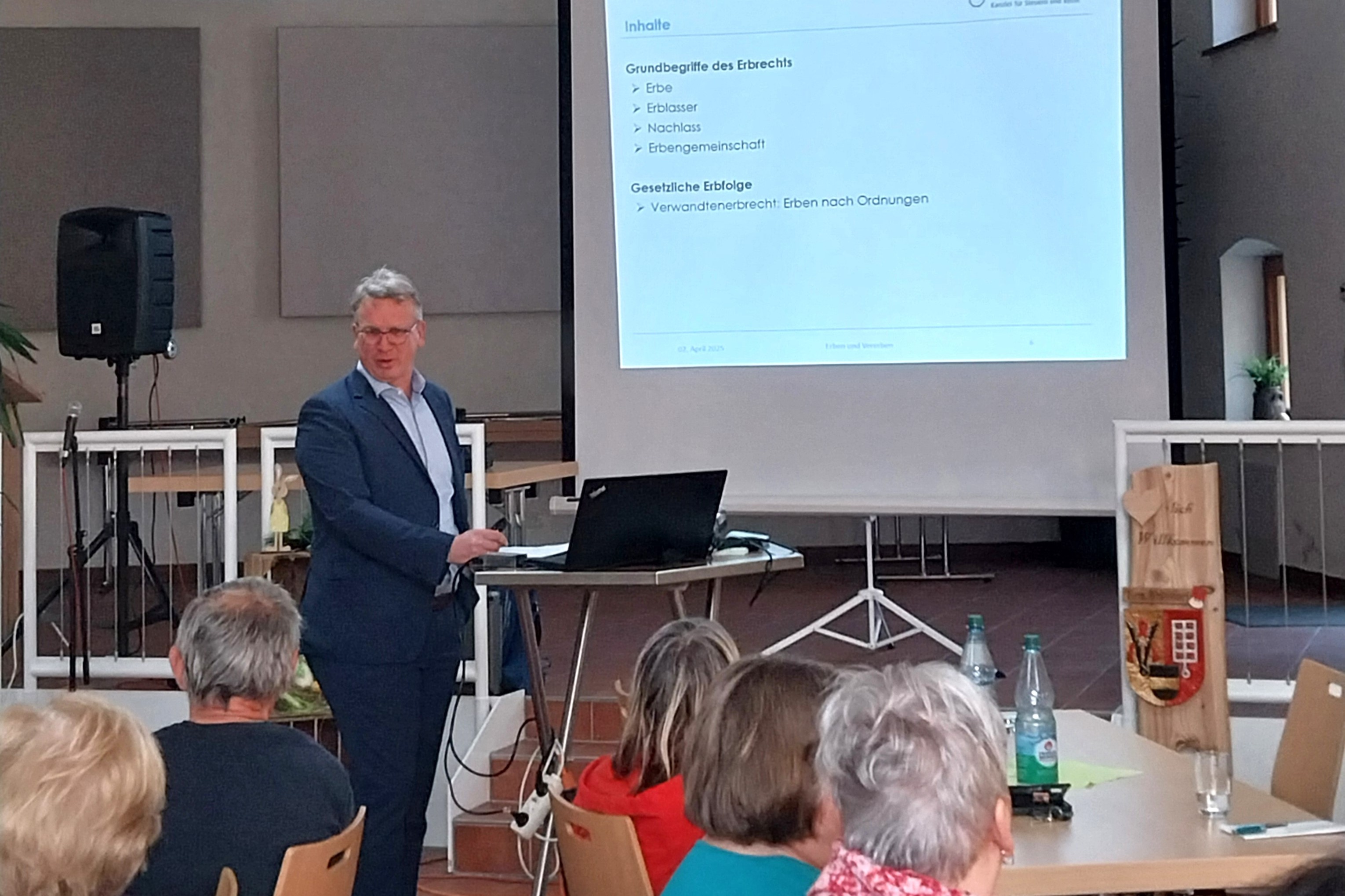 Referent steht vor einer Leinwand und spricht zum Publikum.